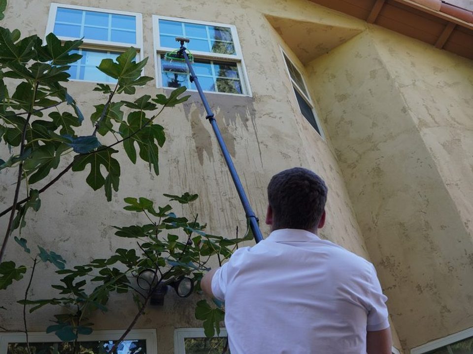 ORCA cleaning a second-story window with a water-fed pole